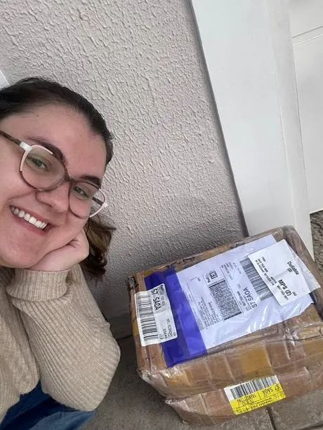 Aluna recebendo a caixa da importação em casa
