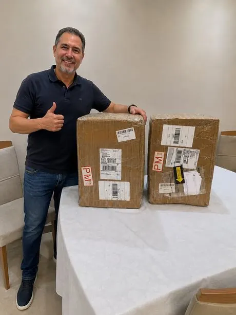 Aluno com duas caixas recebidas, comemorando
